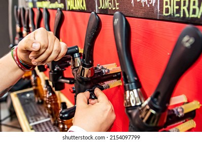 Bartender Hand At Beer Tap Pouring A Draught Beer In Bottle In Tap Room