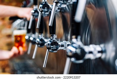 Bartender Hand At Beer Tap Pouring A Draught Beer In Glass Serving In A Bar Or Pub. Tap Room