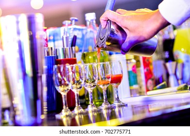 Bartender hand with shaker and cocktails, The bartender, Bartender pours alcoholic drink into glasses - Powered by Shutterstock