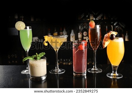 bartender make special colourful assorted cold cocktail or mocktail fruit juice in tall shot glass goblet on black table luxury hotel pub iced alcohol beverage bar menu