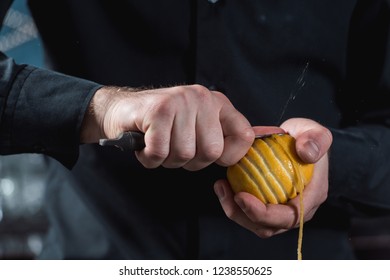 Bartender Making Cocktail. Slicing A Long Ribbon Of Lemon Peel