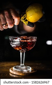 Bartender Making Cocktail. Slicing A Long Ribbon Of Lemon Peel