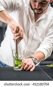 Bartender mashed with a muddler mint leaf and lime for mojito cocktail