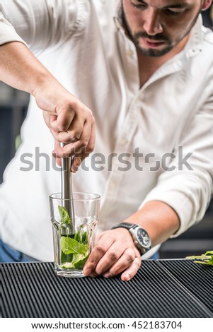 Bartender mashed with a muddler mint leaf and lime for mojito cocktail