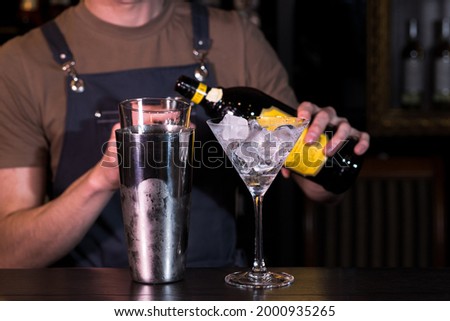 The bartender at the nightclub behind the bar making an Espresso Martini cocktail
