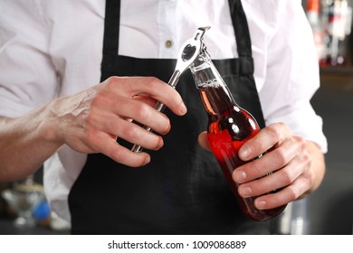 bartender opens a bottle of beer