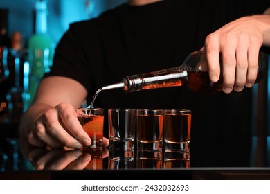 Bartender pouring alcohol drink into shot glass at mirror counter in bar, closeup - Powered by Shutterstock