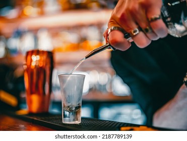 bartender pouring alcohol into a shot glass in bar