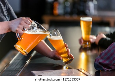 Bartender Pouring Beer From A Pitcher At A Brew Pub