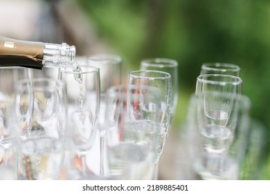 Bartender Pouring Champagne Or Wine Into Wine Glasses On The Table At The Outdoors Solemn Wedding Ceremony. 