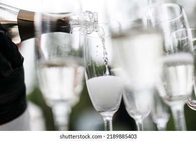 Bartender Pouring Champagne Or Wine Into Wine Glasses On The Table At The Outdoors Solemn Wedding Ceremony. 