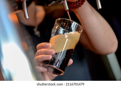 Bartender Pouring Dark Beer Into A Glass From A Tap
