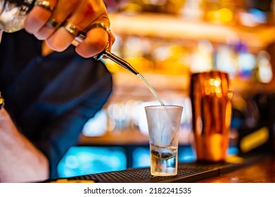 bartender pouring distilled alcohol into a shot glass in bar