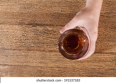 Bartender Pouring A Drink. Top View Of Bartender Hand With Glass Of Whisky 