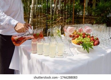 Bartender Pouring Juice From Pitcher Into Glass At Wedding Reception