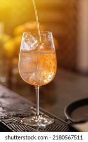 Bartender Pouring Prosecco In Wine Glass With Ice Cube. Long Fizzy Drink.