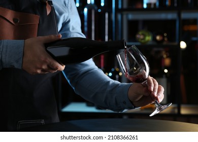 Bartender pouring red wine from bottle into glass indoors, closeup - Powered by Shutterstock