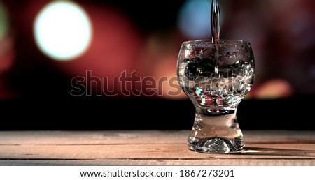 Bartender pouring up tequila into shot glass.