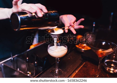 Bartender pouring using strainer White pink healthy Cocktail drink on a bar counter . Bartender view . Trendy stylish white. Copy paste for purple neon design people luxury service barman in nightclub