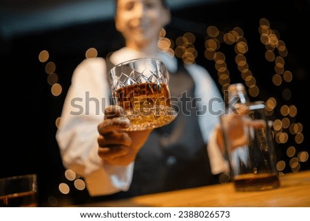 Bartender is pouring whiskey  glasses for customers beautiful night.