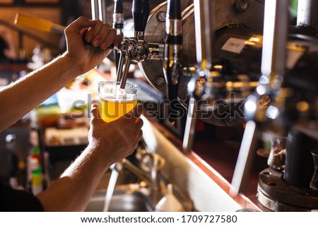bartender pours beer into a glass from the tap bar menu horizontal