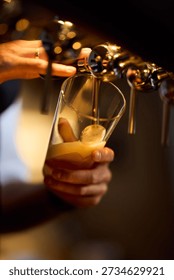 A bartender pours draft beer into a glass, foamy beer forming as the tap flows. Warm bar lighting and a soft blurred background create a cozy, inviting nightlife vibe.