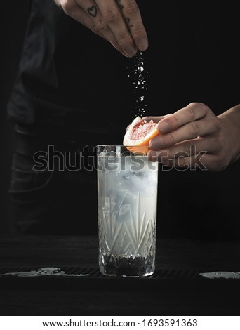 the bartender prepares cocktail with grapefruit