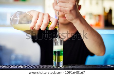 bartender prepares a colorful cocktail on the bar table in restaurant