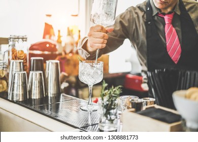 Bartender preparing cocktail with gin , rosemary and pink pepper inside vintage bar - Lifestyle, nightlife, quality drinks and entertainment jobs concept - Focus on barman hand