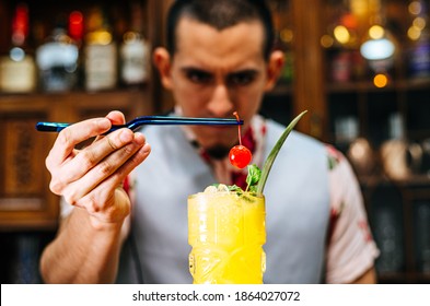 Bartender putting a cherry on a tiki cocktail