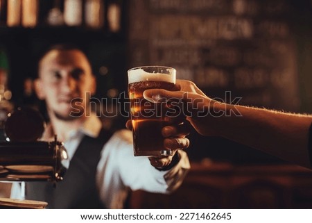 bartender serves a glass of light draft beer to a male guest at bar