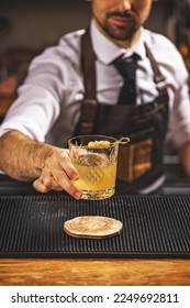Bartender serving a ginger cocktail on the bar counter