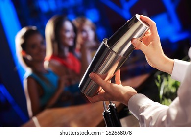 Bartender shaking a cocktail, young women on the background - Powered by Shutterstock