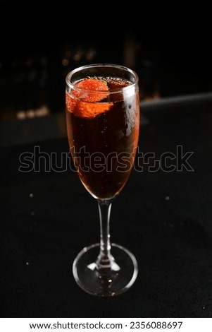 bartender special cold red wine cocktail or mocktail fruit juice soda with strawberry in tall glass goblet on black table luxury hotel pub iced alcohol beverage bar menu