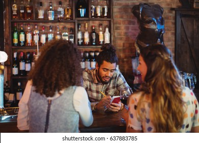 Bartender taking an order on notepad at counter in pub - Powered by Shutterstock