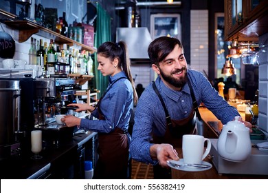 Bartender waiter with a kettle and mug of coffee tea working in