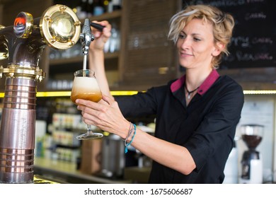 Bartender woman with blond hair serving beer at restaurant bar. - Powered by Shutterstock