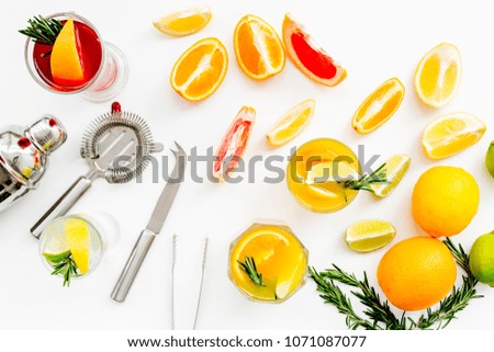 Bartender workplace for make fruit cocktail with alcohol. Shaker, strainer and other bar tools near citrus fruits and glass with cocktail on white background top view pattern
