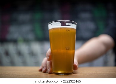 Bartender's Hand Hold Full Glass Of Craft Beer In A Bar Or Tap Room