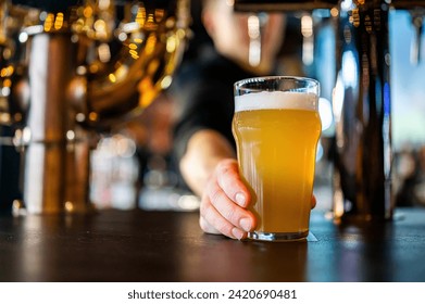 bartender's hand hold full glass of craft beer in a bar  - Powered by Shutterstock