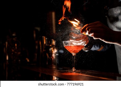 Bartender`s hands making a fresh alcoholic cocktail with a smoky note on the dark bar counter - Powered by Shutterstock