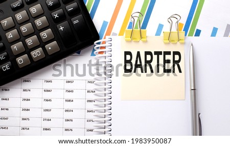 BARTER text, written on a sticker with calculator,pen on chart background.