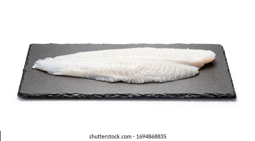 Basa Fish Fillet On A Black Stone Plate, Isolated On White Background.