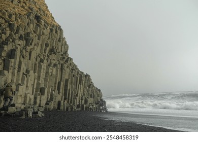 Basalt columns on the beach at Reynisfjara. Reynisdrangar Cliffs, Halsanefshellir, a sea cave that's famous for its hexagonal basalt pillars. It's located on the Reynisfjara black sand beach. - Powered by Shutterstock