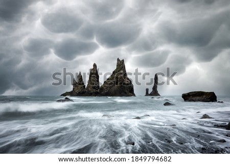 Basalt rock formations Troll toes on black beach with stormy sky with menacing mammatus clouds on background. Reynisdrangar, Vik, Iceland