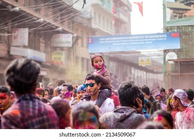 Basantapur, Kathmandu, Nepal - March 1, 2018: Father carrying a little girl on his shoulder to show the crowd during Holi Festival.