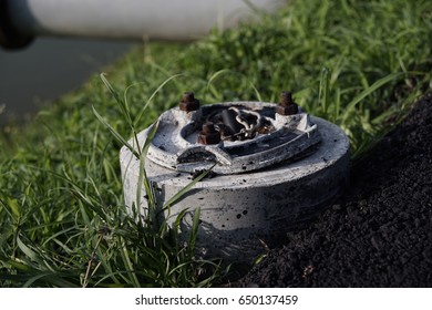 Base Of Broken Lamp Post On The Grass In The Public Park.