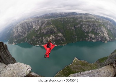 BASE jumper jumping off a big cliff in Norway with a red windsuit, breathtaking