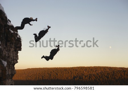 Base jumper jumps down from a high rock against the background of the forest edge in the evening light. Compilation of the phases of the athlete's movement during the jump. Base jumping.