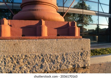 Base Of Pillar Supporting Building On Concrete Plinth With Glass Wall Facade Behind